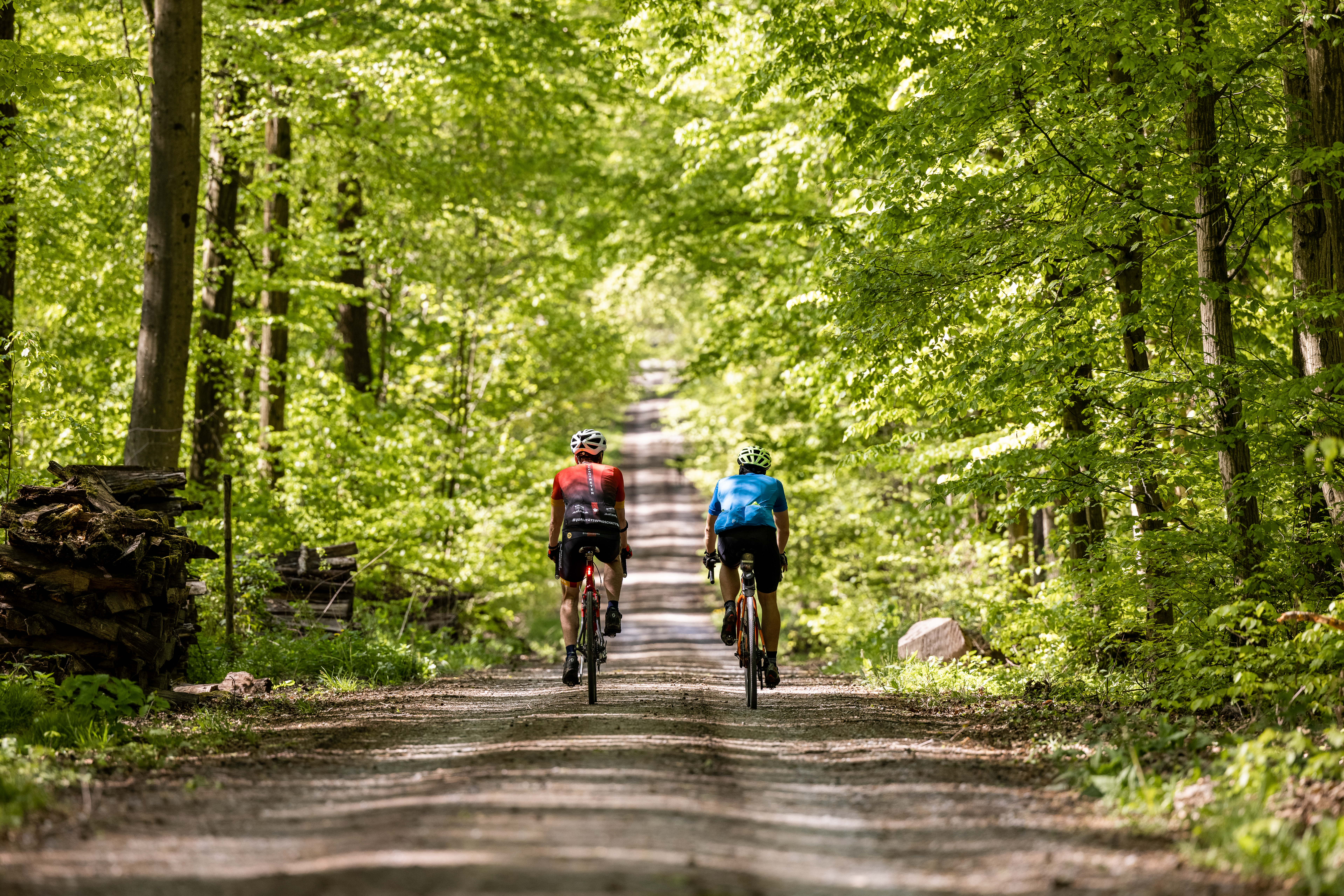 2 Fahrradfahrer auf Schotterweg durch den Wald. Perfektes Gravel-Feeling im Land der 1000 Hügel.