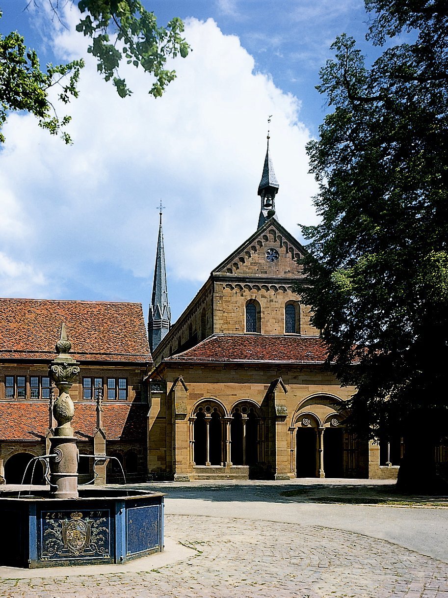 Blick auf die Klosterkirche mit Klausur, davor Brunnen und Lindenbäume