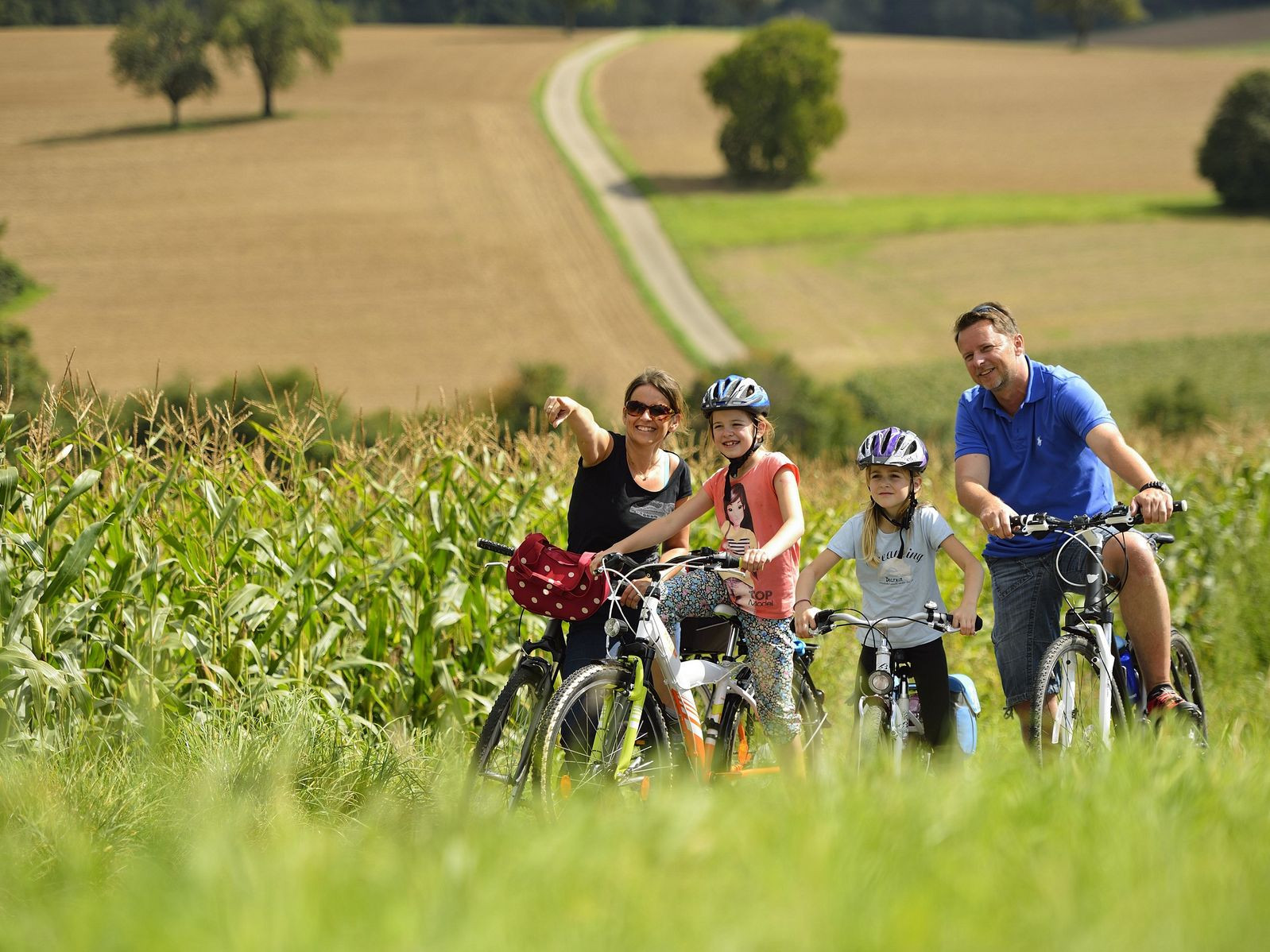 Familie auf Fahrrädern vor einem Maisfeld